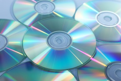 Photo of Many shiny compact discs on dusty blue background, closeup