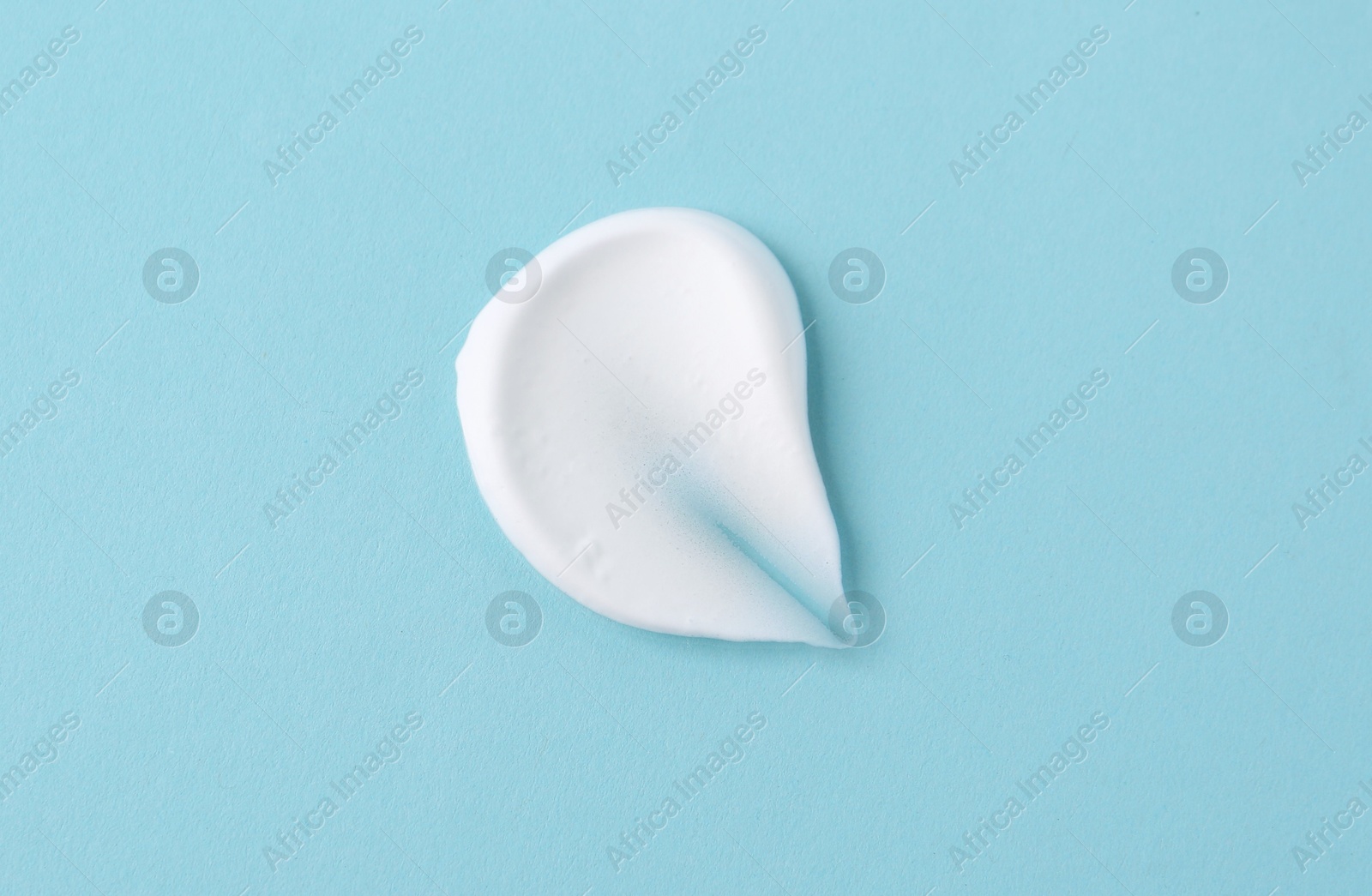 Photo of Sample of fluffy foam on light blue background, top view