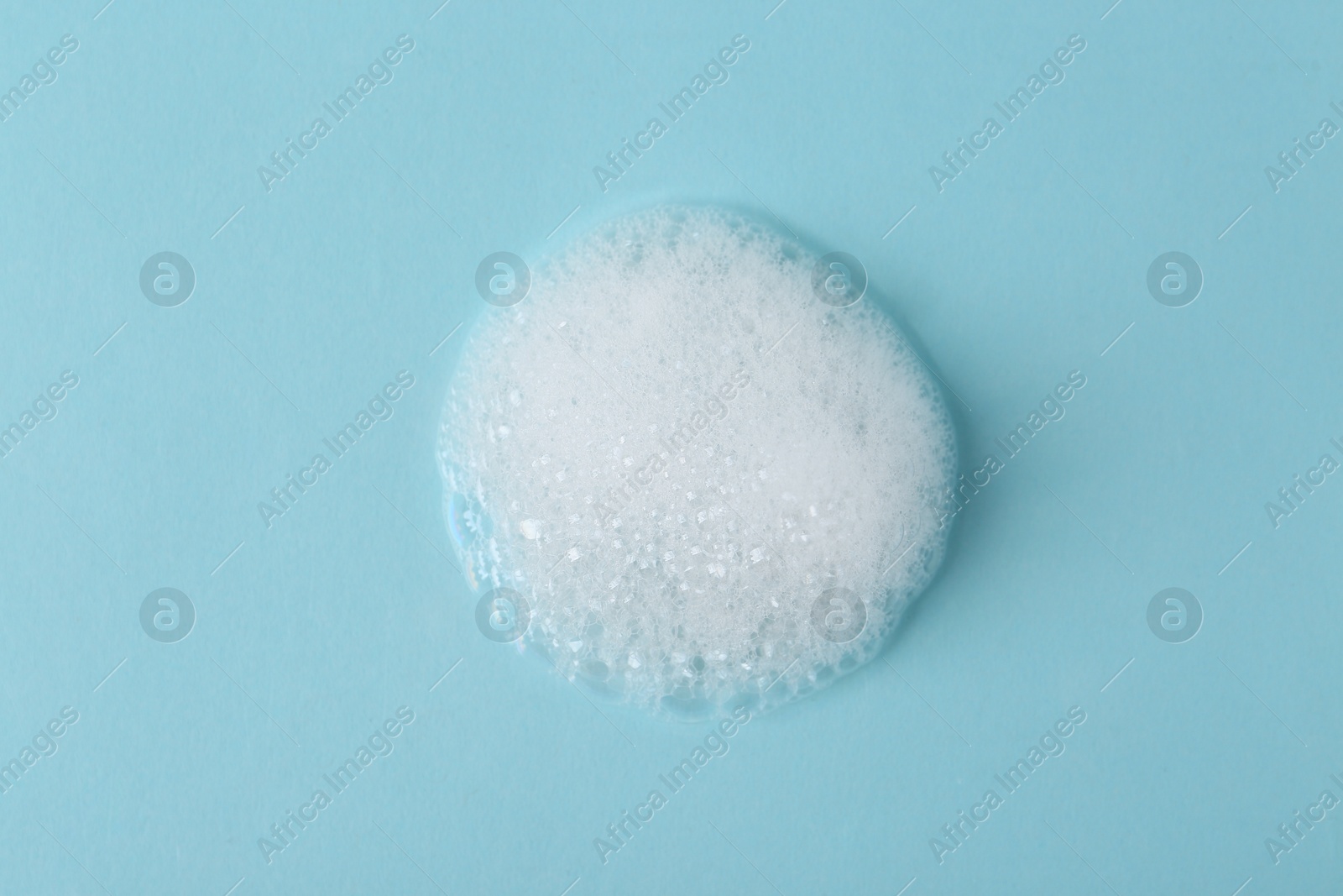 Photo of Sample of fluffy foam on light blue background, top view