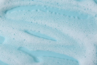 Photo of White fluffy foam on light blue background, top view