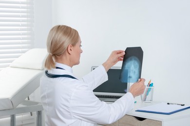 Photo of Doctor examining x-ray image of paranasal sinuses at table in clinic