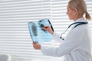 Photo of Doctor examining x-ray image of lungs in clinic, space for text