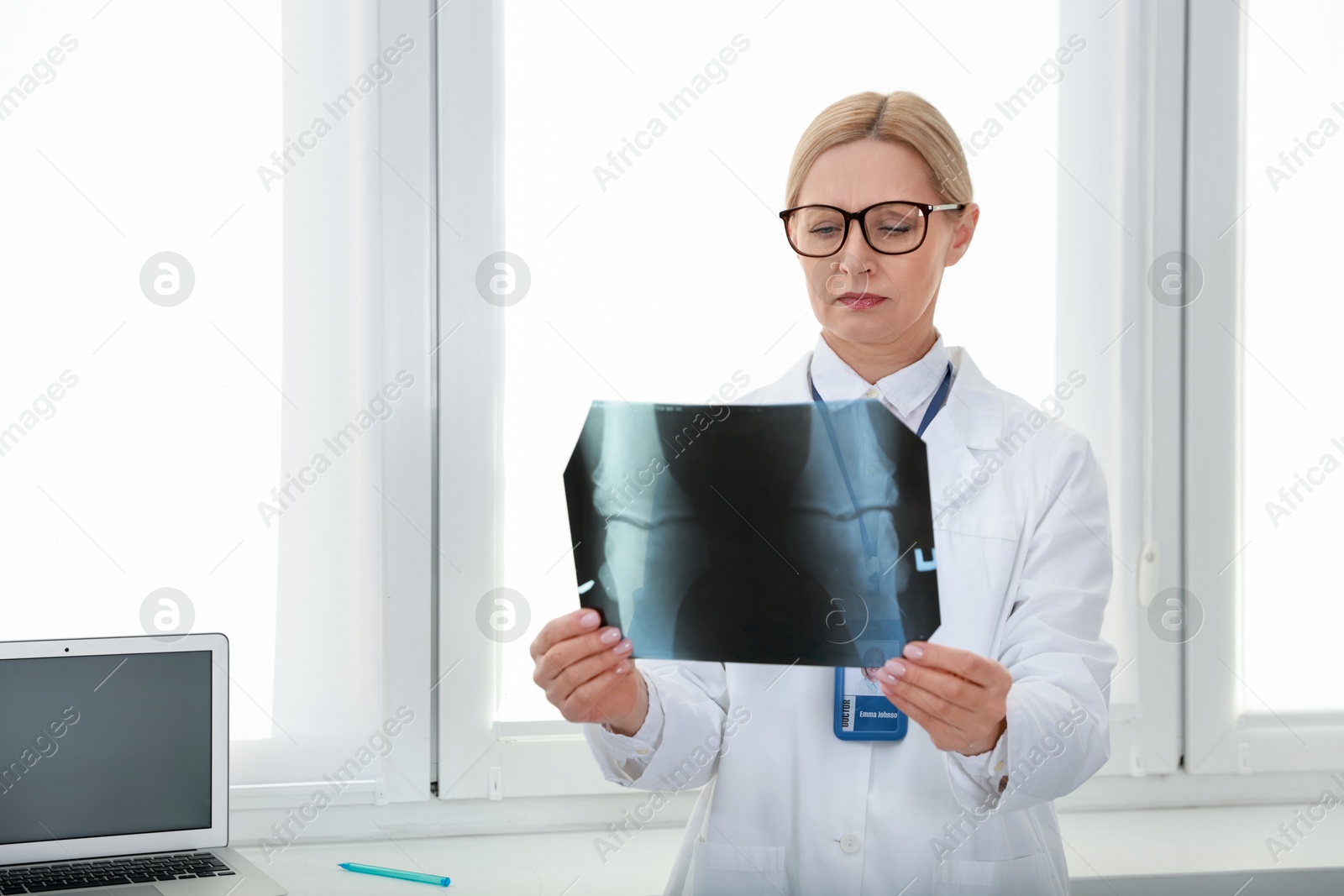 Photo of Doctor examining knee x-ray near window in clinic