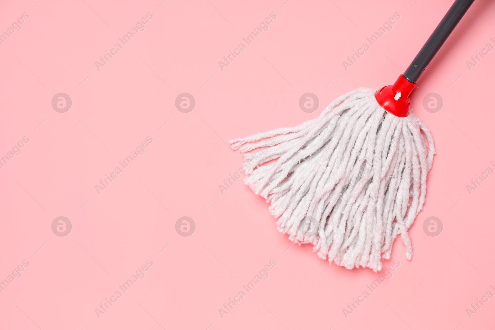 Photo of String mop on pink background, above view. Space for text