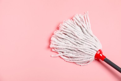 Photo of String mop on pink background, above view. Space for text