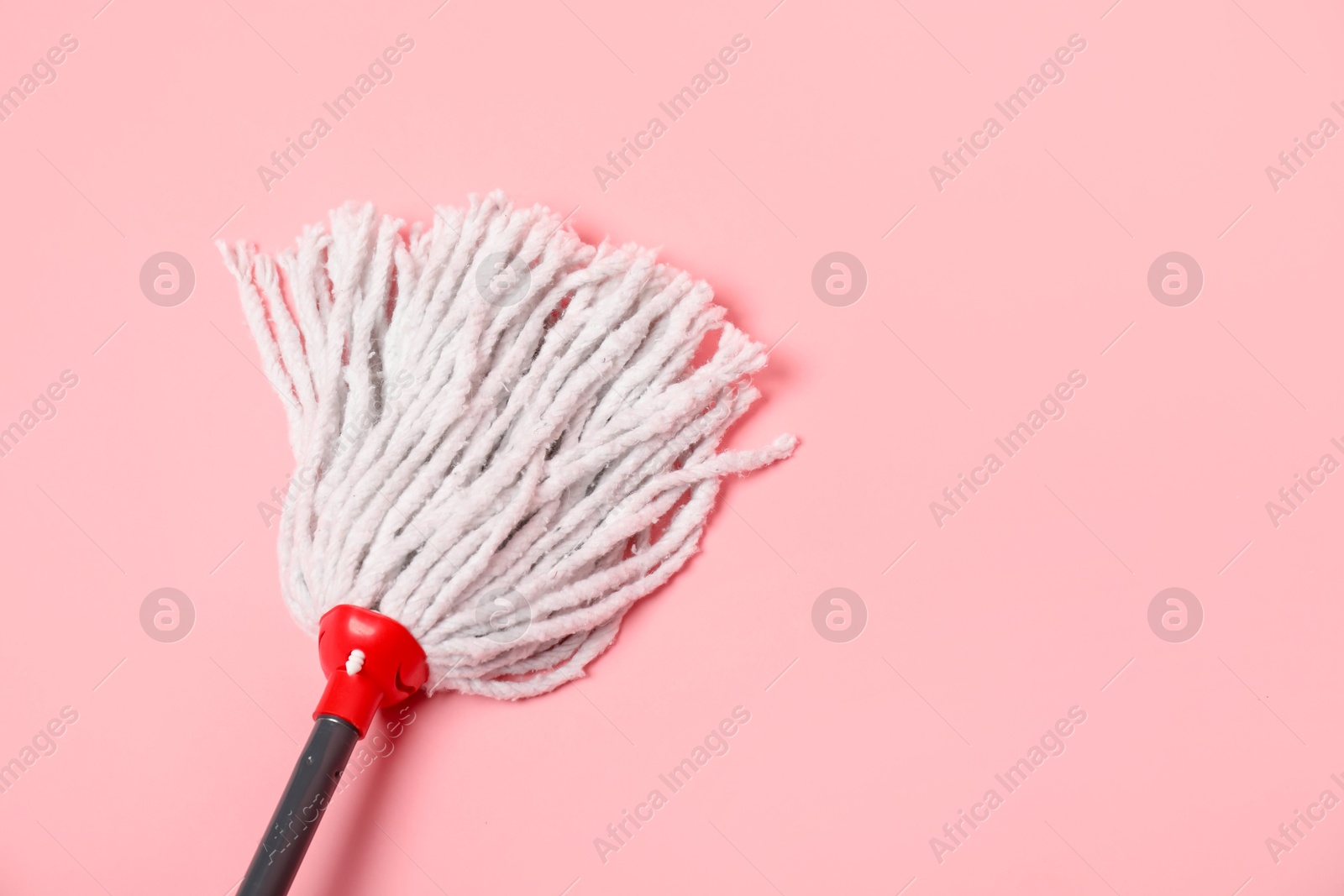 Photo of String mop on pink background, above view. Space for text