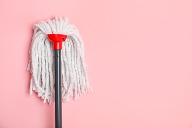 Photo of String mop on pink background, top view. Space for text