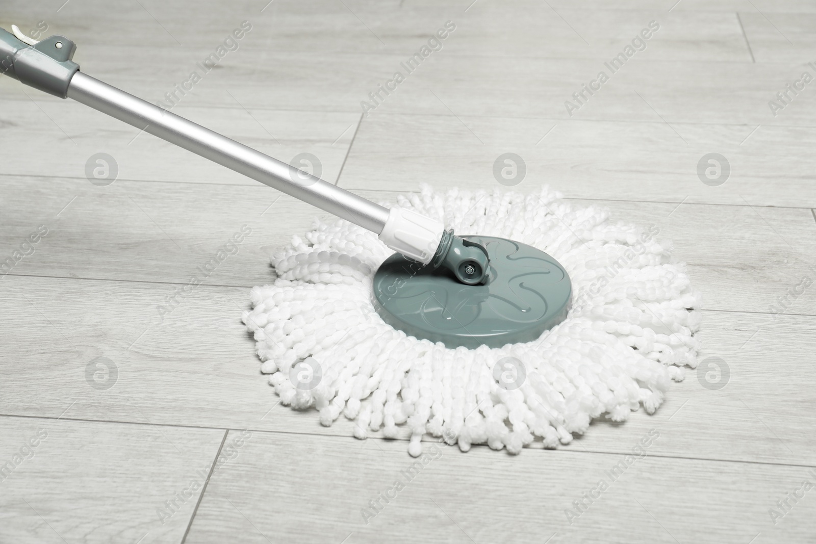 Photo of String mop on wooden floor. Cleaning equipment