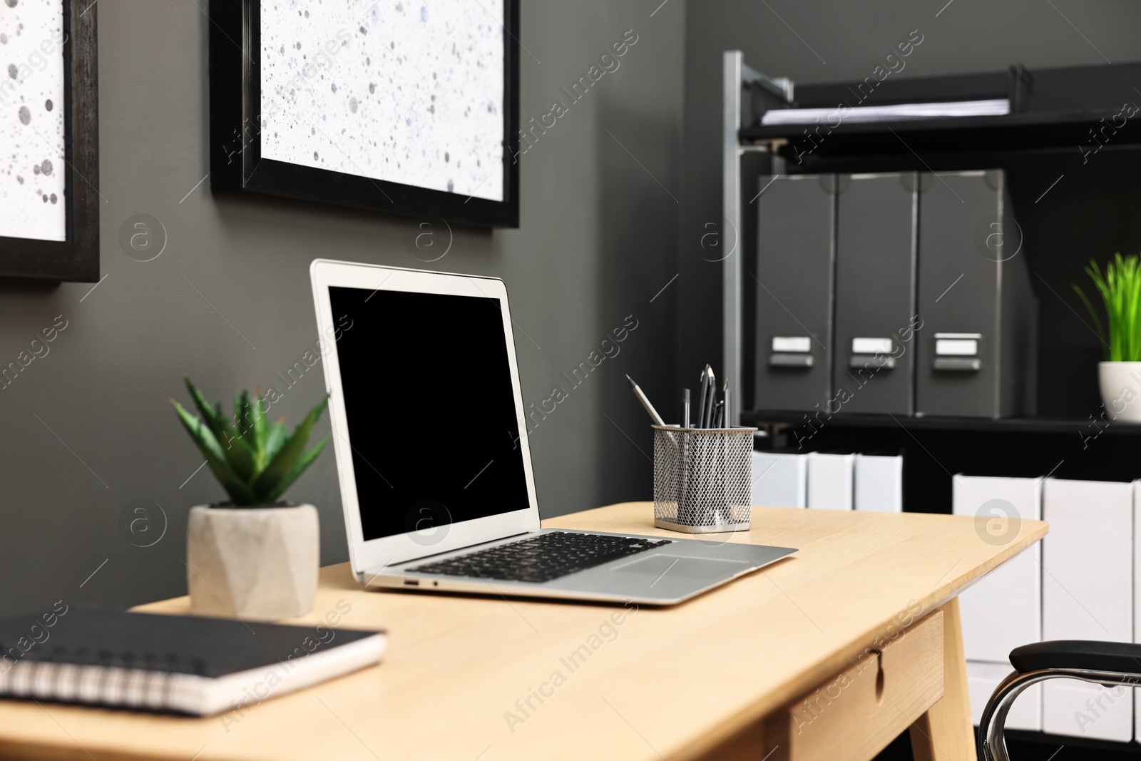 Photo of Comfortable workplace with modern laptop on wooden table indoors