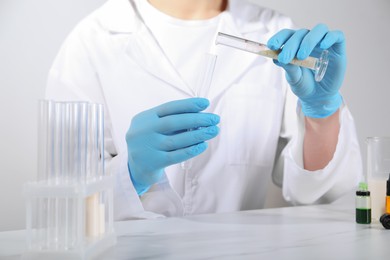 Photo of Laboratory testing. Scientist working with test tubes at white marble table, closeup