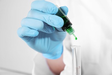 Photo of Laboratory testing. Scientist dripping liquid into test tube, closeup