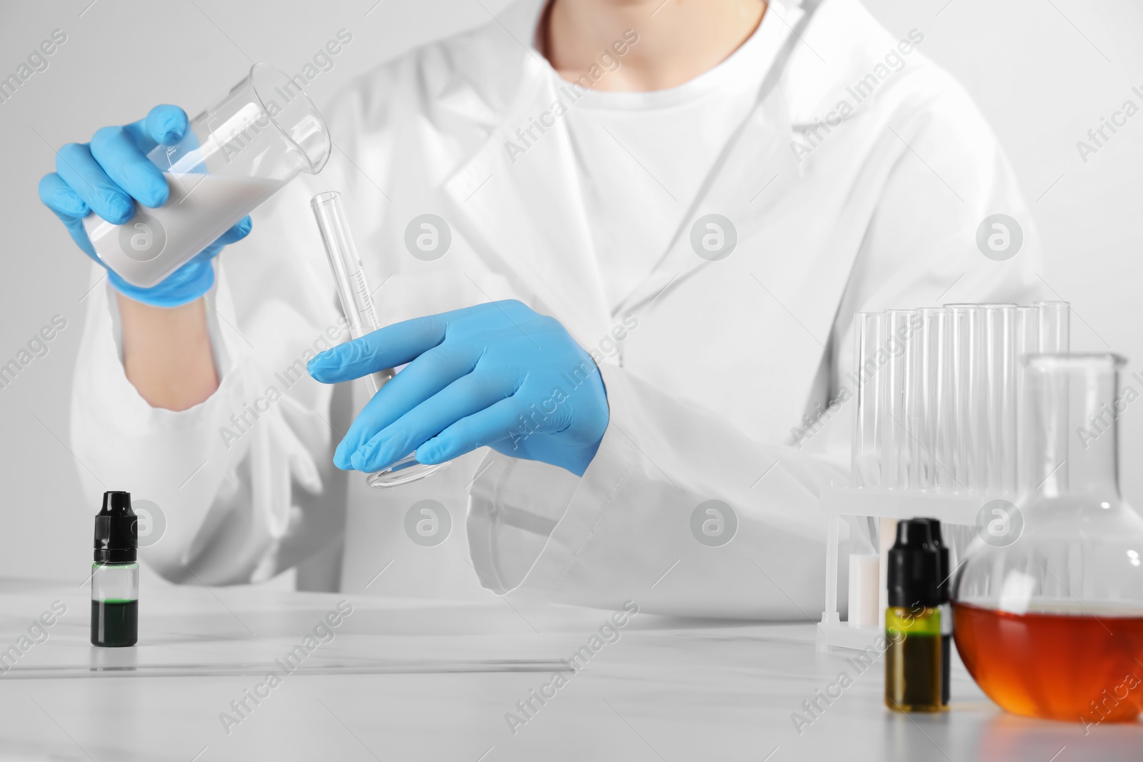 Photo of Laboratory testing. Scientist working with glassware at white marble table, closeup