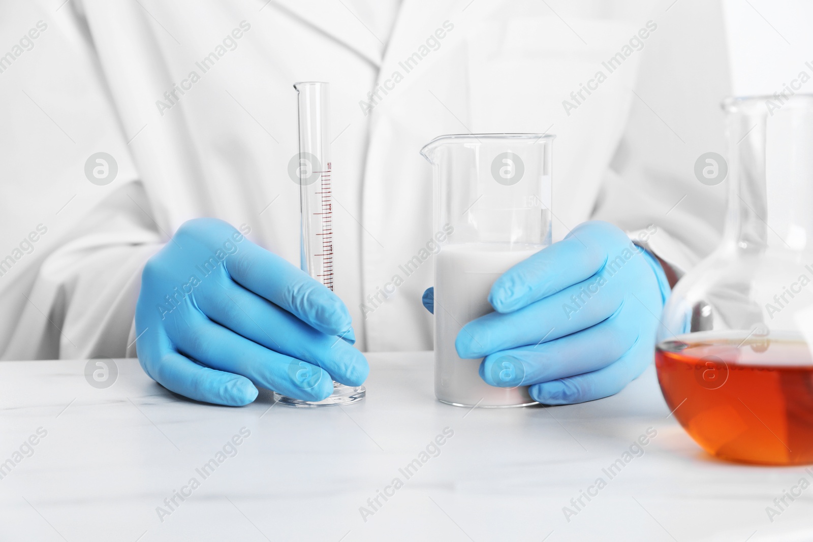 Photo of Laboratory testing. Scientist working with glassware at white marble table, closeup