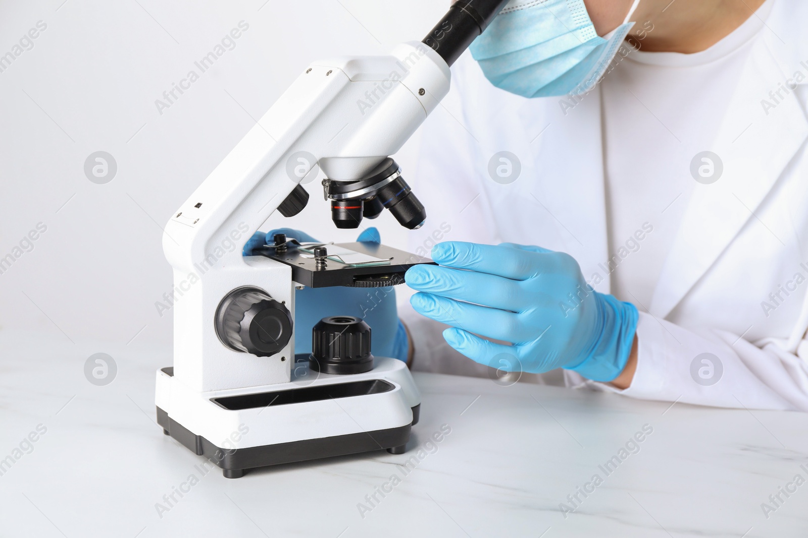 Photo of Laboratory testing. Scientist working with microscope at white marble table, closeup