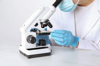 Photo of Laboratory testing. Scientist working with microscope at white marble table, closeup