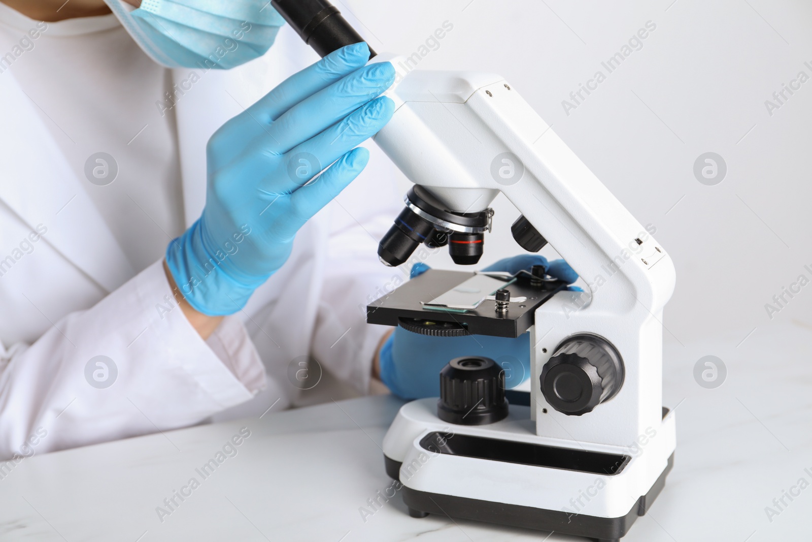 Photo of Laboratory testing. Scientist working with microscope at white marble table, closeup