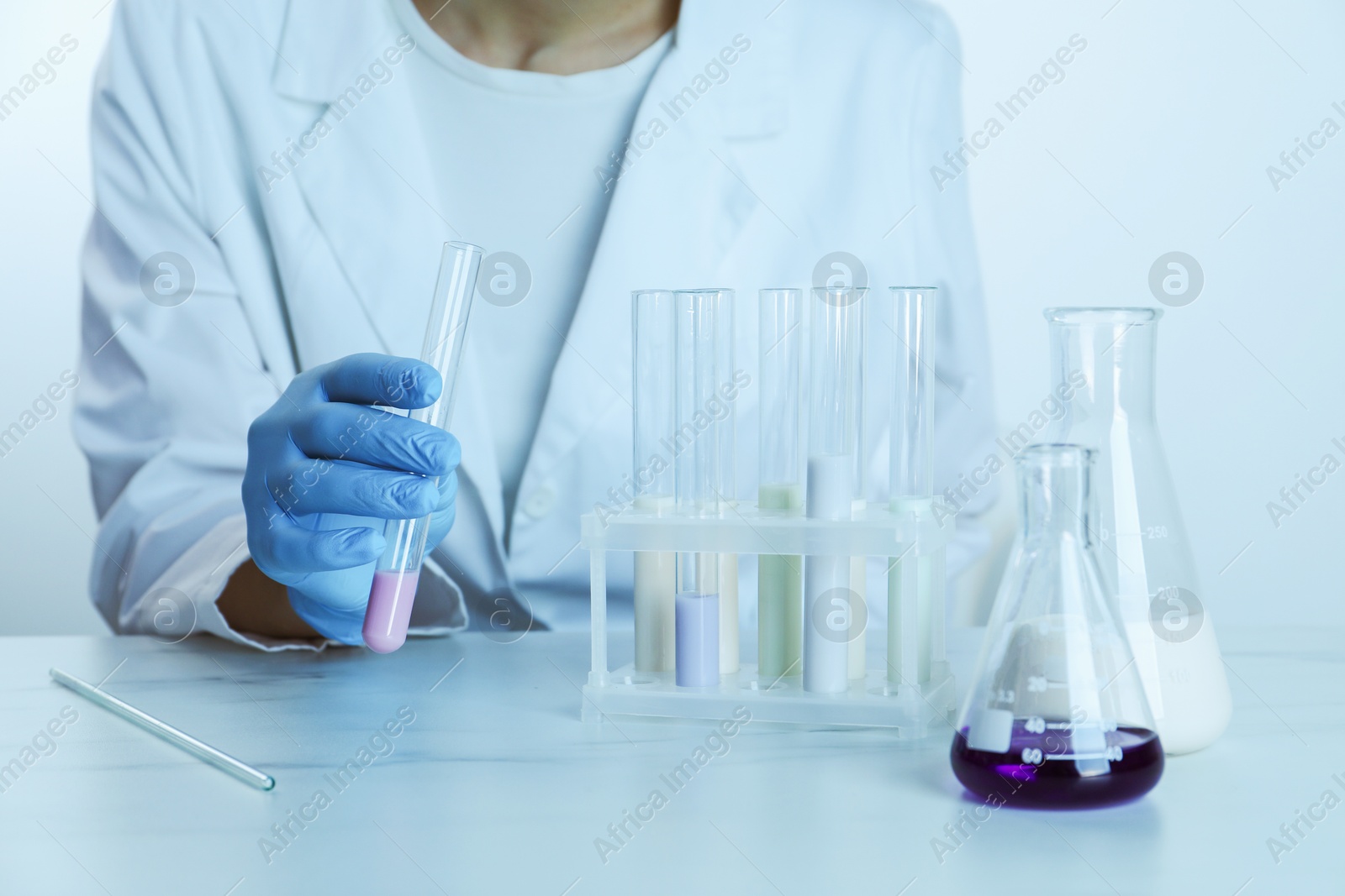 Photo of Laboratory testing. Scientist working with glassware at table, closeup. Toned in blue