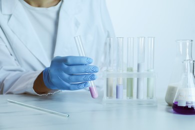 Photo of Laboratory testing. Scientist working with glassware at table, closeup. Toned in blue