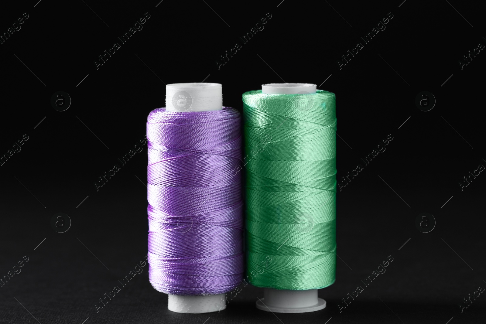 Photo of Spools of colorful sewing threads on black background