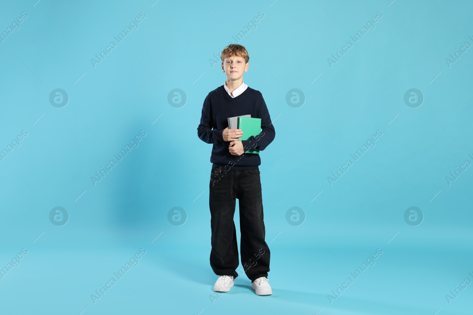 Photo of Full length portrait of teenage boy with books on light blue background