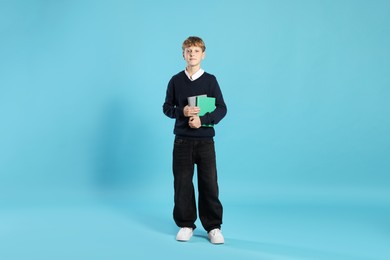 Photo of Full length portrait of teenage boy with books on light blue background