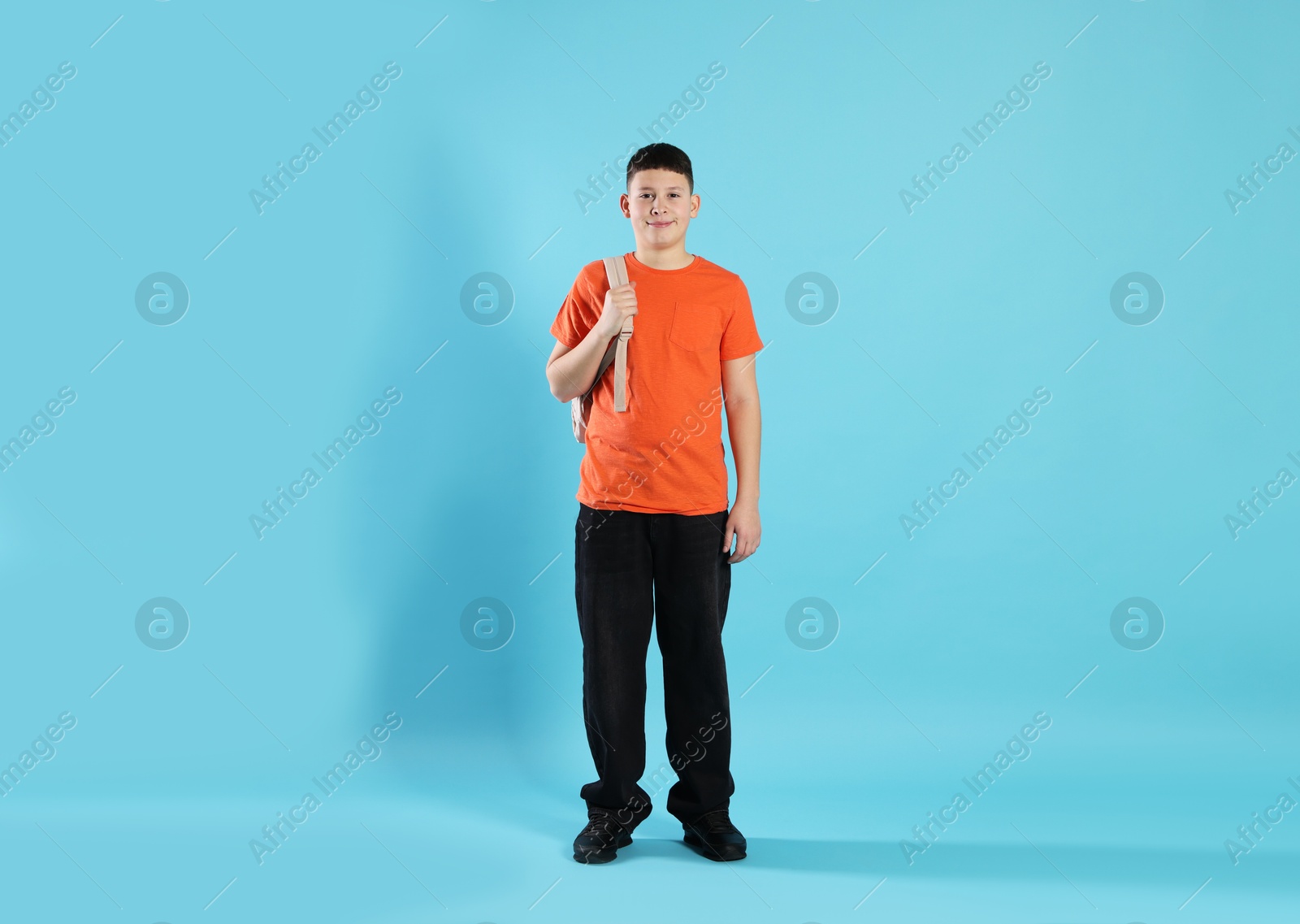 Photo of Full length portrait of teenage boy with backpack on light blue background