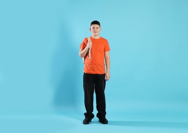 Photo of Full length portrait of teenage boy with backpack on light blue background