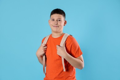 Photo of Portrait of teenage boy with backpack on light blue background