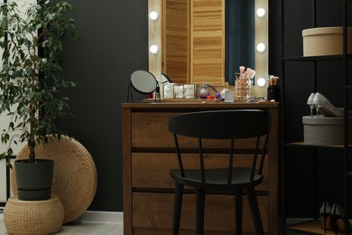 Photo of Makeup room. Mirrors, different beauty products, shoes, dresser and chair indoors