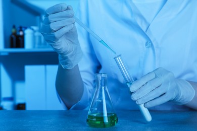 Photo of Laboratory testing. Scientist dripping sample into test tube at table indoors, closeup