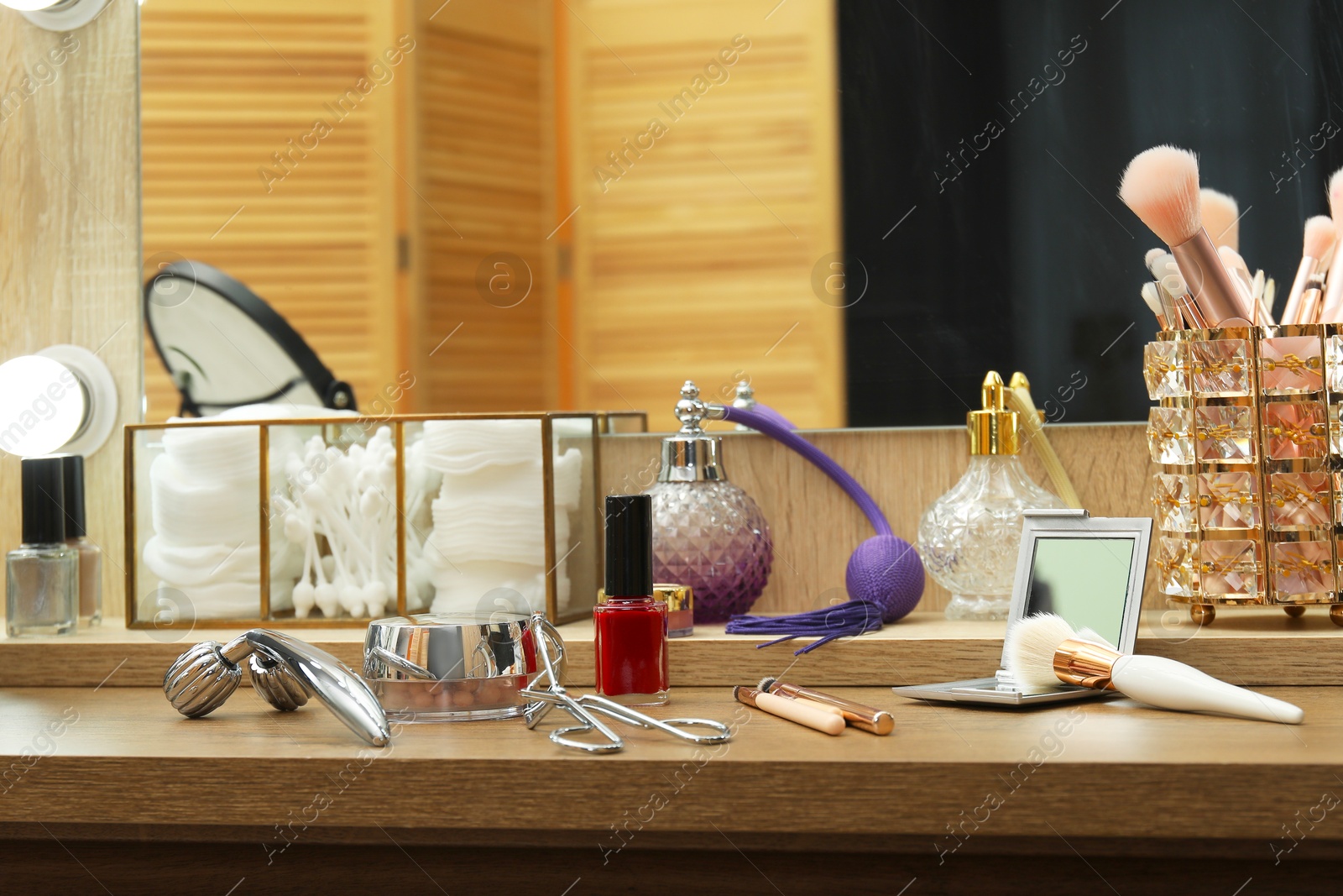 Photo of Makeup room. Different beauty products on wooden dressing table and mirror indoors, closeup