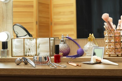 Photo of Makeup room. Different beauty products on wooden dressing table and mirror indoors, closeup