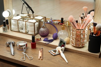 Photo of Makeup room. Different beauty products on wooden dressing table indoors