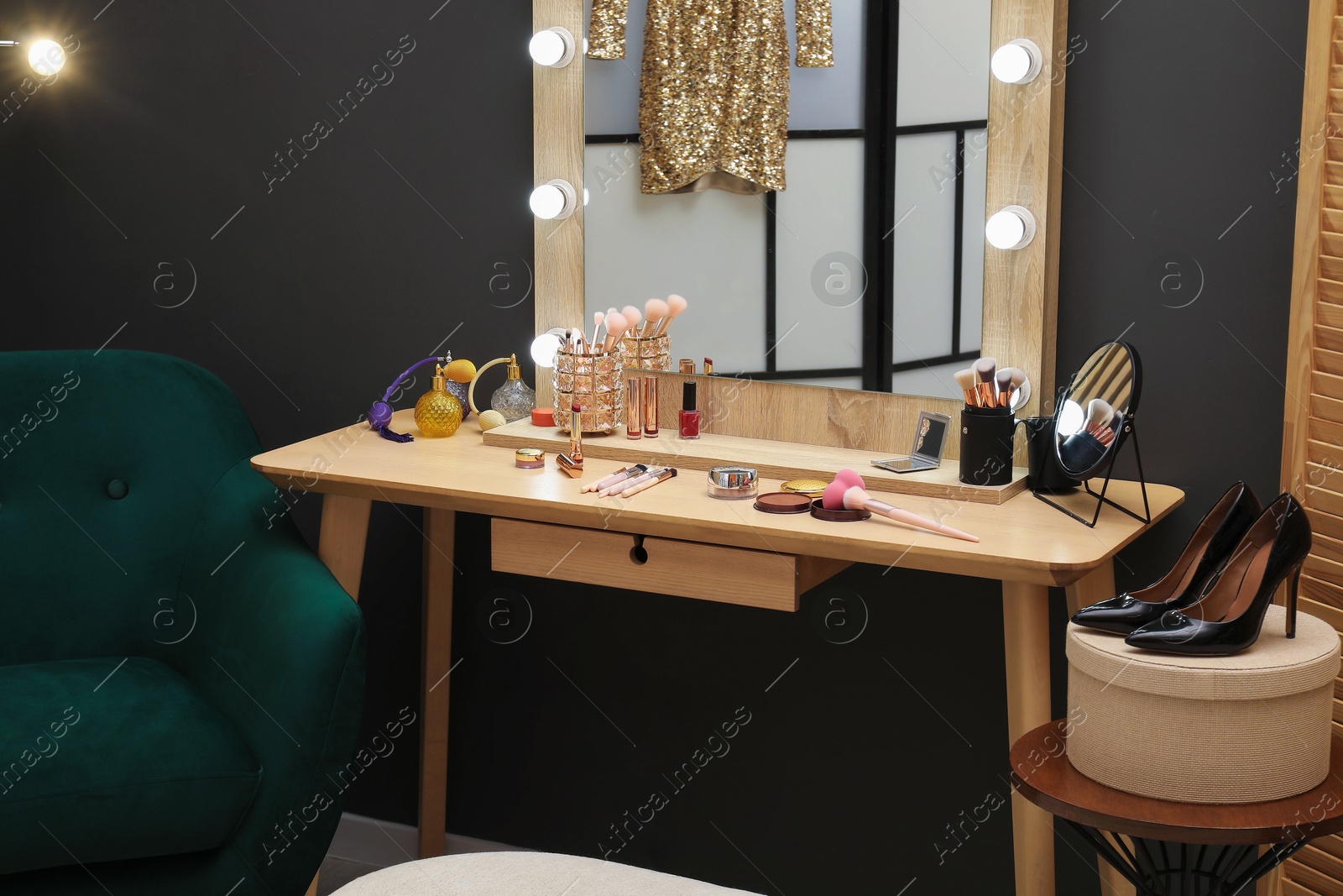 Photo of Makeup room. Wooden dressing table with mirror, different beauty products, shoes and armchair indoors