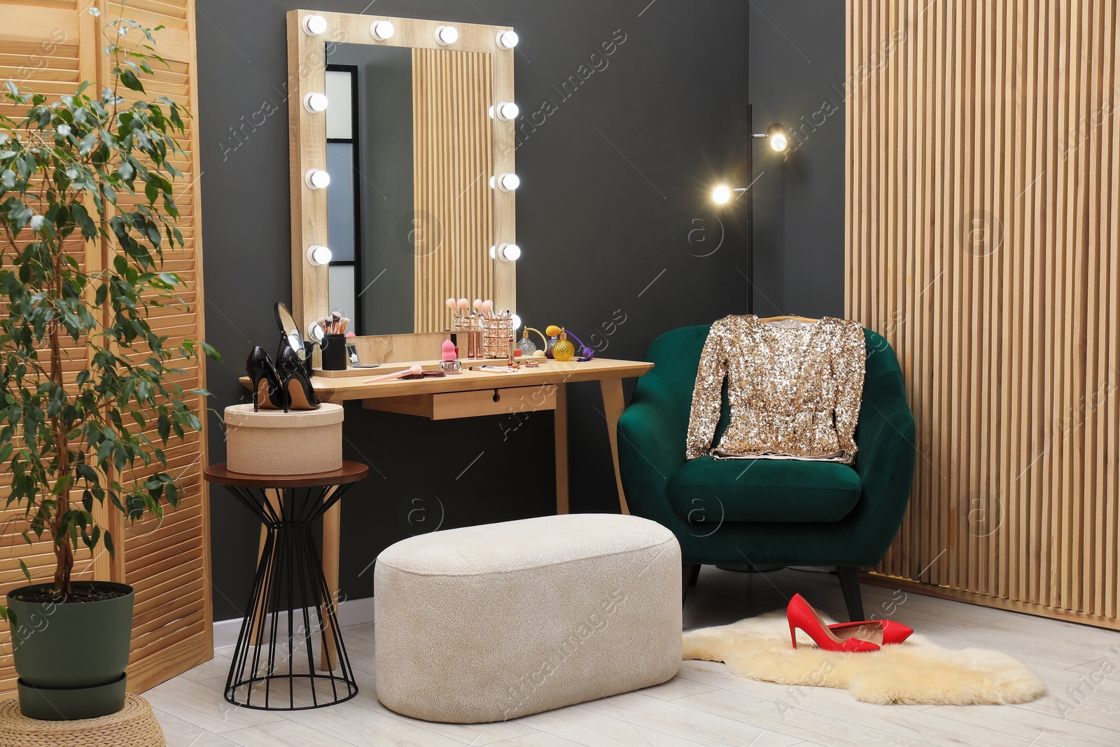 Photo of Makeup room. Wooden dressing table with mirror, different beauty products, shoes and pouf indoors