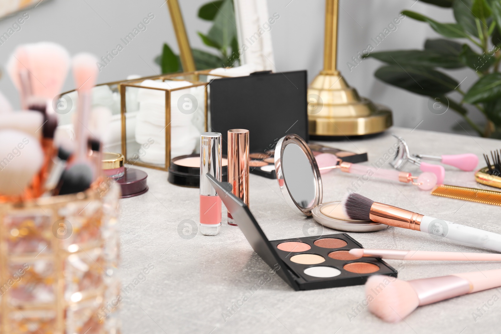 Photo of Makeup room. Different beauty products on grey dressing table and mirror indoors, closeup