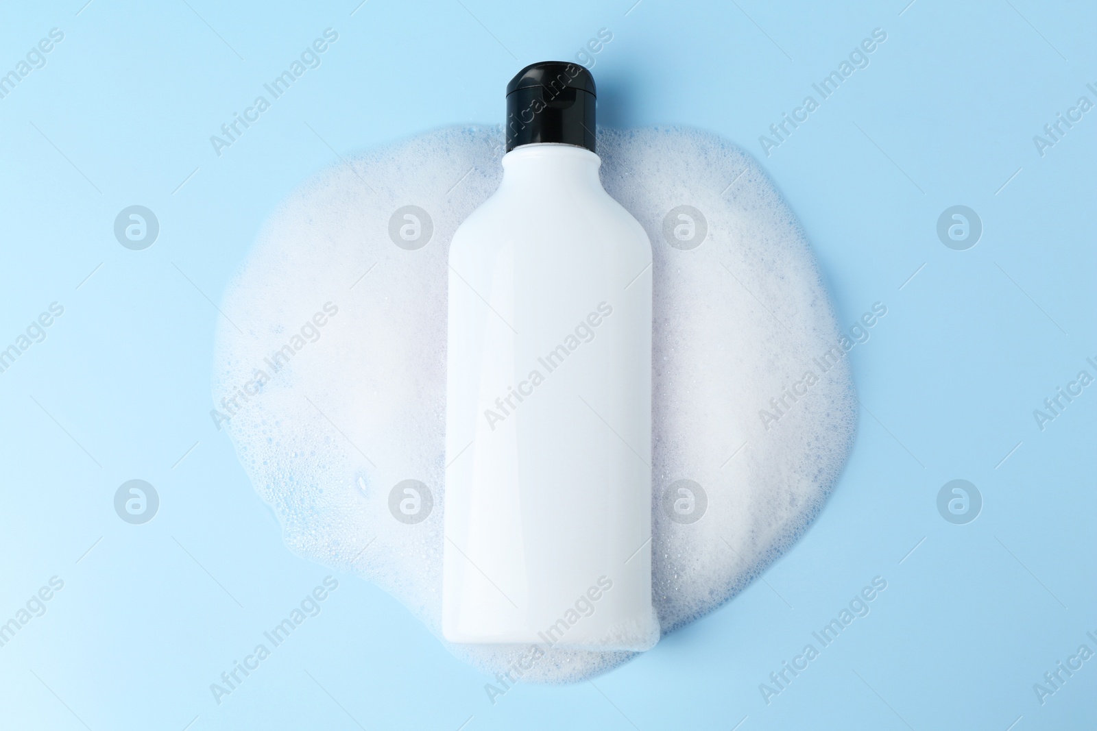 Photo of Bottle of cosmetic product with foam on light blue background, top view