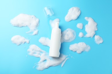 Photo of Bottle of cosmetic product with foam on light blue background, top view