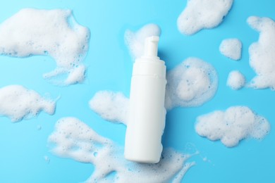 Photo of Bottle of cosmetic product with foam on light blue background, top view