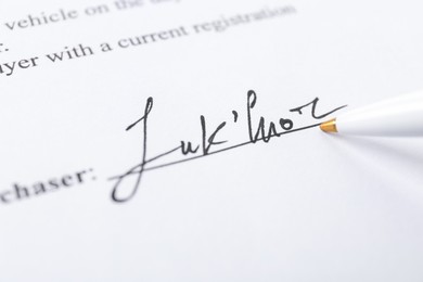 Photo of Signature and pen on paperwork, closeup view