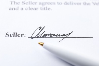 Photo of Signature and pen on paperwork, closeup view