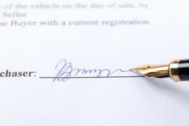 Photo of Fountain pen leaving signature on contract, closeup