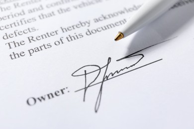 Photo of Signature and pen on paperwork, closeup view