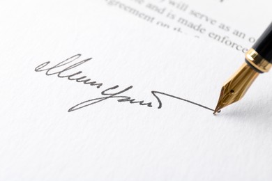 Photo of Fountain pen leaving signature on paper, closeup