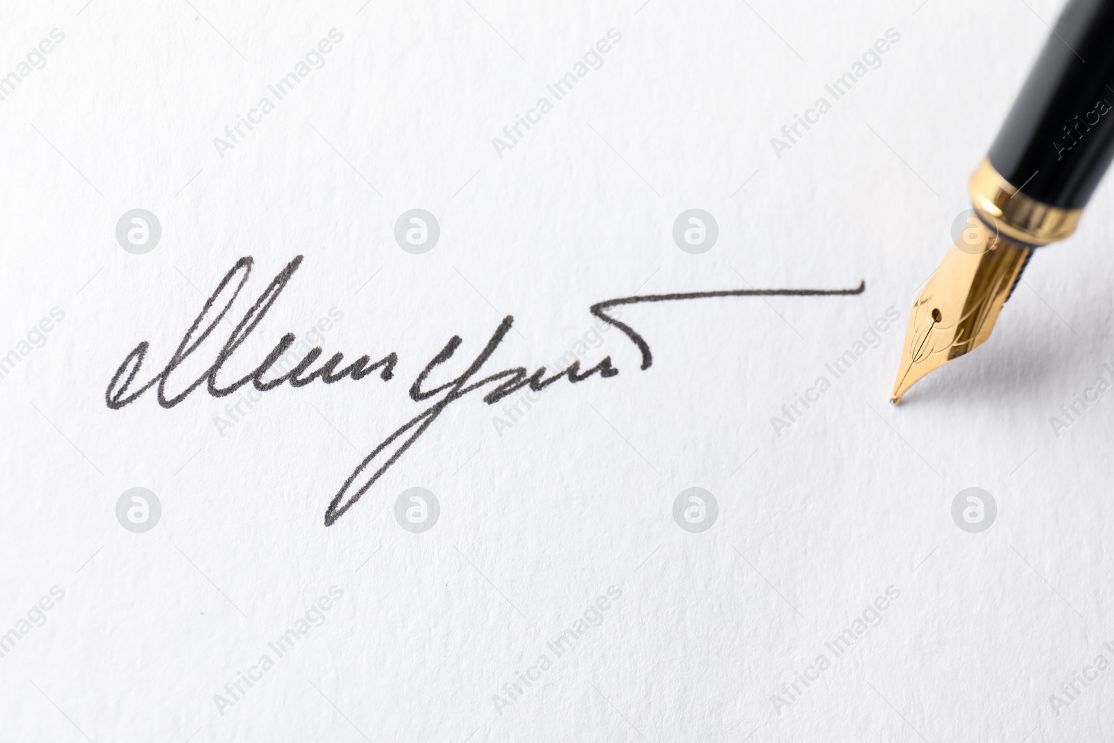 Photo of Fountain pen leaving signature on paper, closeup