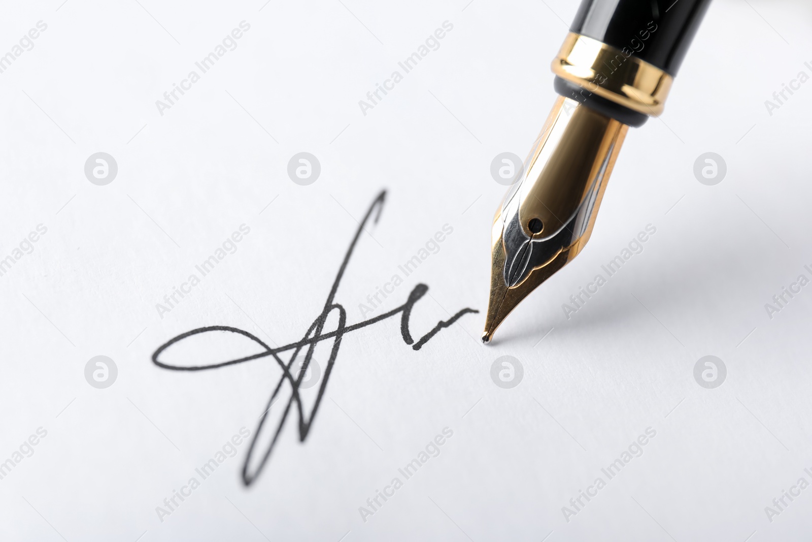 Photo of Fountain pen leaving signature on paper, closeup