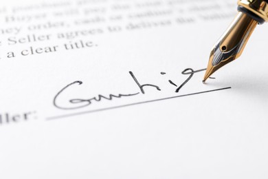 Photo of Fountain pen leaving signature on contract, closeup