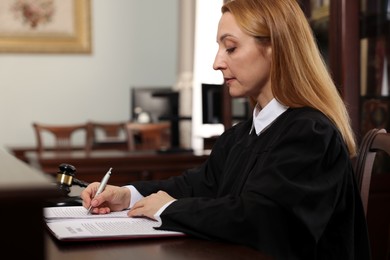 Photo of Judge in court dress working at table indoors