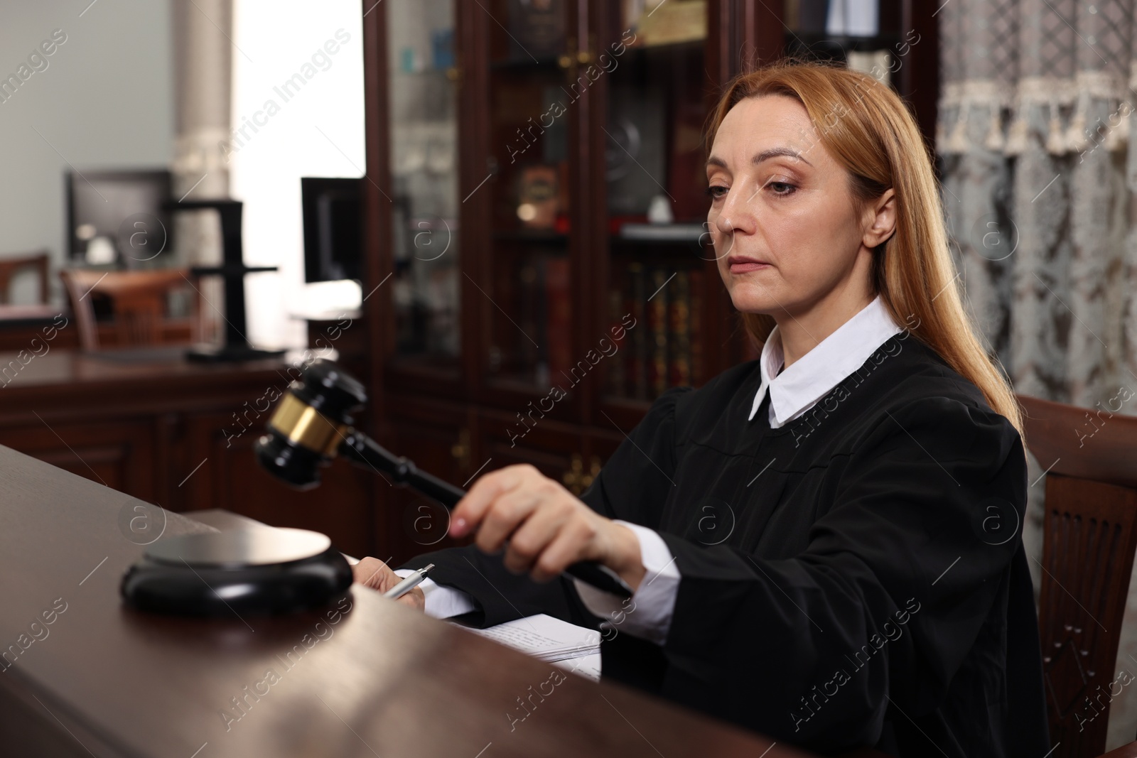 Photo of Judge striking gavel at wooden table in courtroom