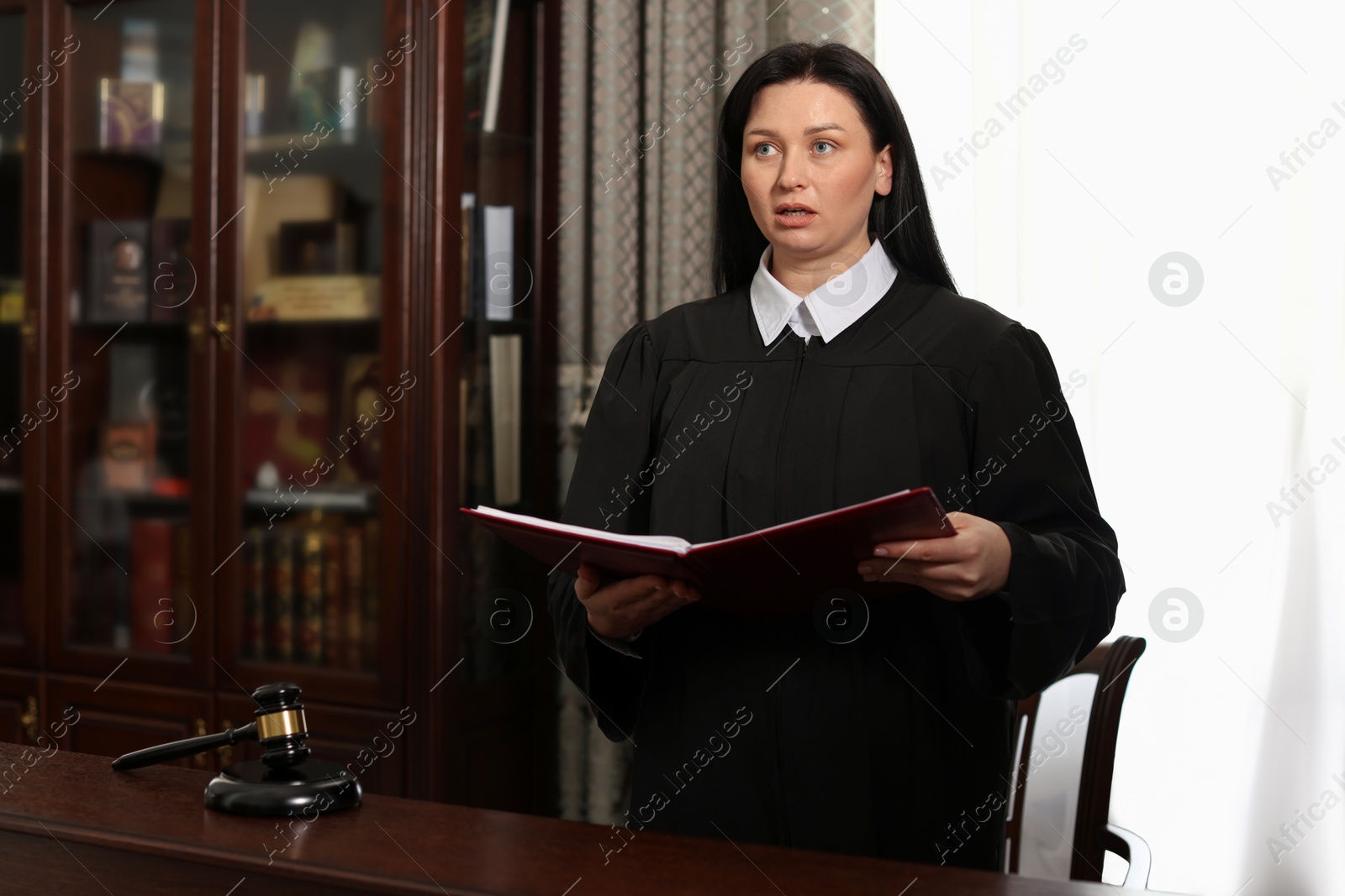 Photo of Judge with folder of documents at table in courtroom